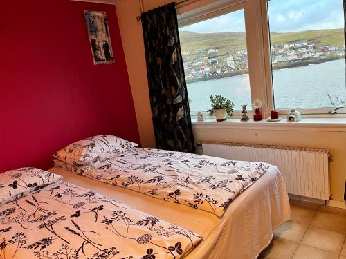The Atlantic view guest house, Sandavagur, Faroe Islands في Sandavágur: غرفة نوم بسرير ونافذة