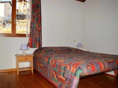 - une chambre avec un lit doté d'une couverture colorée et d'une fenêtre dans l'établissement Charmant T3 avec Parking, Proche des Pistes, Equipé pour Familles - FR-1-593-14, aux Angles