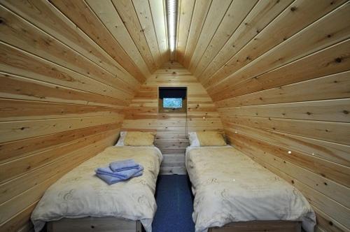 een kamer met 2 bedden in een houten hut bij Wolds Glamping in Pocklington