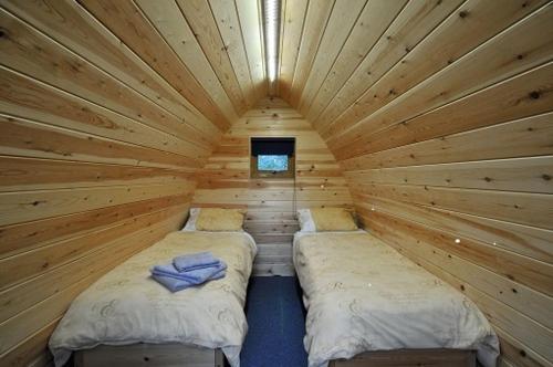 a room with two beds in a wooden cabin at Wolds Glamping in Pocklington