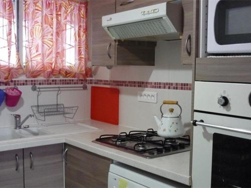 une petite cuisine avec une cuisinière et un micro-ondes dans l'établissement Appartement cosy 2 pièces cabine, proche commerces et pistes, 6 pers, animaux OK - FR-1-592-20, à Bolquère-Pyrénées 2000