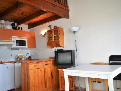 Il comprend une cuisine avec une table blanche et une télévision. dans l'établissement Studio mezzanine avec balcon et parking, plein sud, proche des pistes, 4 pers - FR-1-580-33, à Font-Romeu-Odeillo-Via