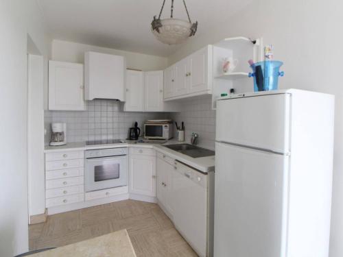 une cuisine avec des armoires blanches et un réfrigérateur blanc dans l'établissement Appartement spacieux 95m2 au pied de la plage avec jardin et parking - FR-1-494-70, à Royan