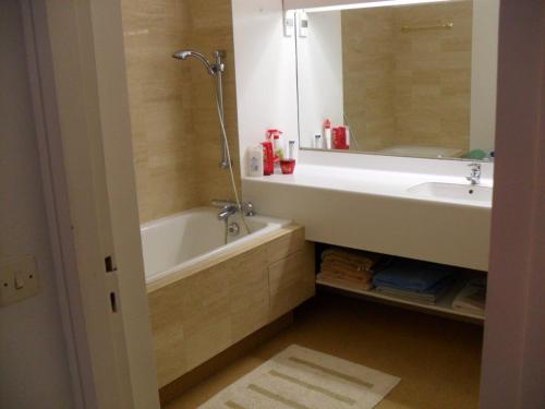 une salle de bain avec une baignoire, un lavabo et un miroir dans l'établissement Appartement spacieux 95m2 au pied de la plage avec jardin et parking - FR-1-494-70, à Royan