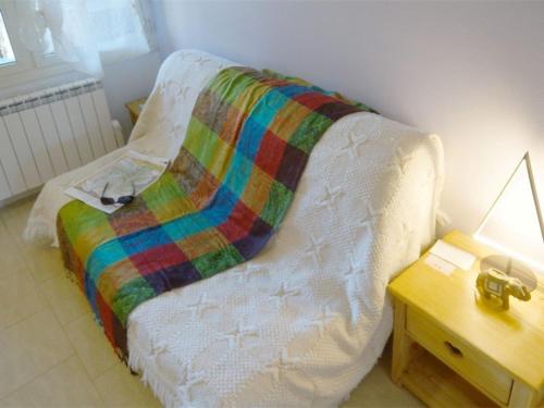 a bed with a colorful blanket on it next to a table at Studio Bagnères-de-Luchon, 1 pièce, 4 personnes - FR-1-313-149 in Luchon