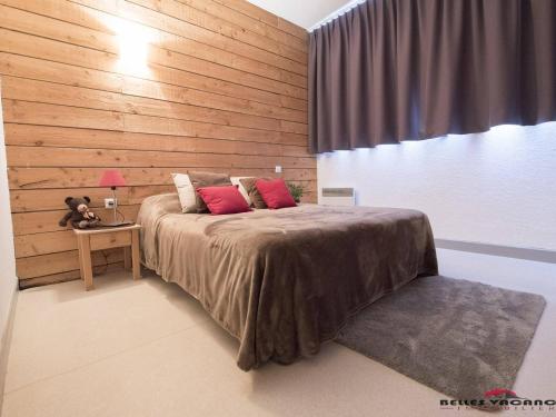 une chambre avec un grand lit avec un mur en bois dans l'établissement Appartement Cozy avec Sauna, Piscine et Proche des Thermes, 4 Pers. à Saint-Lary Village - FR-1-296-328, à Saint-Lary-Soulan