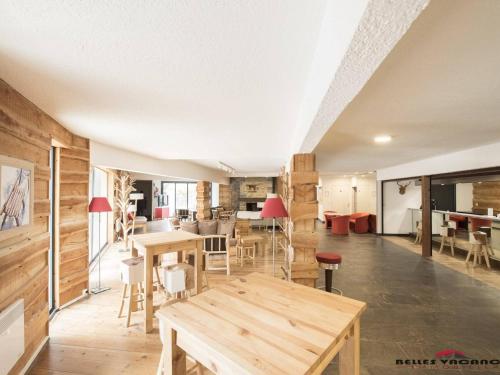 - un salon avec des tables et des chaises en bois dans l'établissement Appartement Cozy avec Sauna, Piscine et Proche des Thermes, 4 Pers. à Saint-Lary Village - FR-1-296-328, à Saint-Lary-Soulan