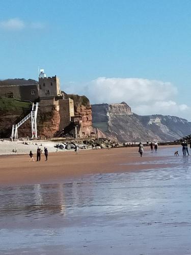 a group of people walking on a beach with a castle at The Groveside Guest House in Sidmouth