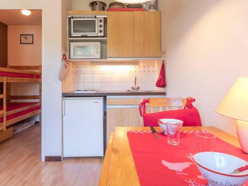 une petite cuisine avec une table et un tapis rouge dans l'établissement Studio cosy avec balcon sud, 3 couchages, Montgenèvre, skis aux pieds, Wifi et ménage inclus - FR-1-330D-14, à Montgenèvre