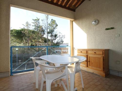 - une table et des chaises blanches dans une chambre dotée d'une grande fenêtre dans l'établissement Grand Studio Climatisé avec Terrasse et Parkings, Proche des Thermes - FR-1-553-106, à Balaruc-les-Bains