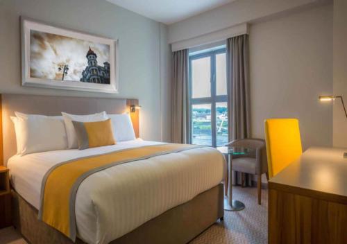 una camera d'albergo con letto, scrivania e finestra di Maldron Hotel Derry a Londonderry