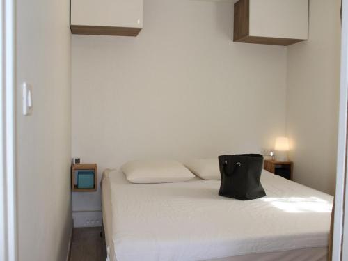 - une chambre dotée d'un lit blanc avec un porte-monnaie noir dans l'établissement Maison avec terrasse, piscine, clim et parking - Gruissan - FR-1-229-779, à Gruissan