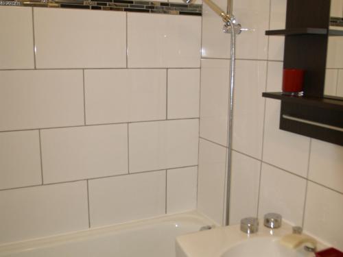 La salle de bains est pourvue de carrelage blanc, d'un lavabo et d'une baignoire. dans l'établissement Studio cabine 4 pers pied des pistes, Les Adrets-Prapoutel - FR-1-557-39, à Les Adrets