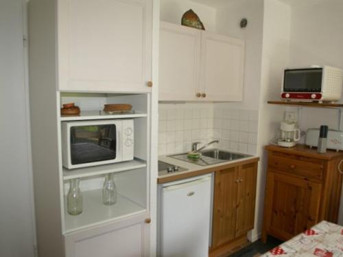une petite cuisine avec des armoires blanches et un micro-ondes dans l'établissement Studio cabine 4 pers pied des pistes, Les Adrets-Prapoutel - FR-1-557-39, à Les Adrets
