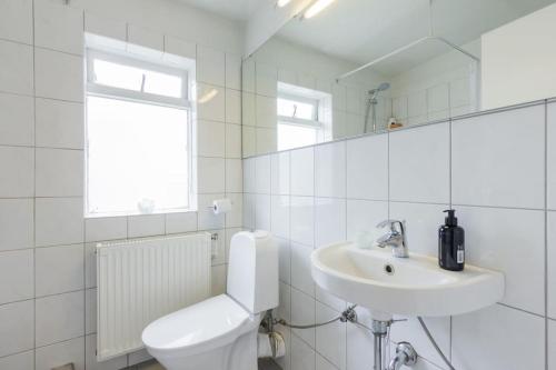 Baño blanco con aseo y lavamanos en Modern and Stylish Reykjavik Apartment, en Reikiavik