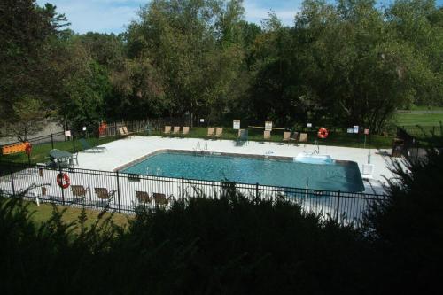 a swimming pool with chairs and a fence around it at Publick House Historic Inn and Country Motor Lodge in Sturbridge