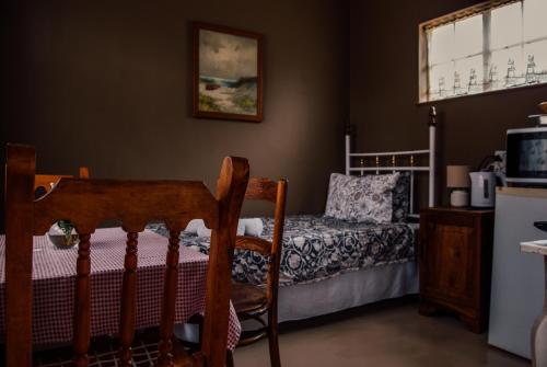 Bloemfontein的住宿－Farm stay at Thyme Cottage on Haldon Estate，卧室配有一张床和一张桌子及椅子
