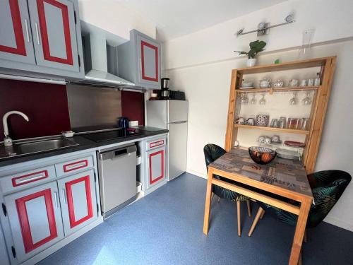 une cuisine avec une table en bois et une petite table avec des chaises dans l'établissement Charmant T1 bis avec terrasse et parking, à 1km des thermes, idéal pour 2 pers, Wi-Fi, Cambo-les-Bains - FR-1-495-90, à Cambo-les-Bains