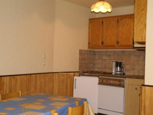 une cuisine avec une table et un réfrigérateur blanc dans l'établissement 2 pièces au pied des pistes, balcon, parking gratuit, proche commerces et ESF - FR-1-557-24, à Les Adrets