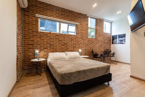 a bedroom with a bed and a brick wall at Soy Local in Medellín