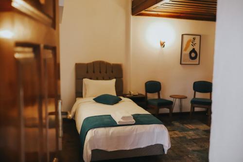 ein Schlafzimmer mit einem Bett mit zwei Stühlen und einem Tisch in der Unterkunft Fibar Hotel Zincirlihan in Aydın