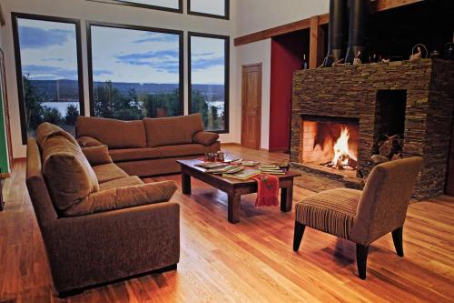a living room with a fireplace and a couch and chairs at Lago Rosario Lodge in Trevelin