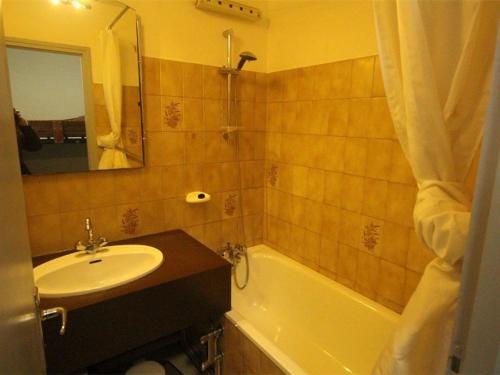 ein Badezimmer mit einem Waschbecken, einer Badewanne und einem Spiegel in der Unterkunft Studio Bagnères-de-Luchon, 1 pièce, 4 personnes - FR-1-313-183 in Luchon