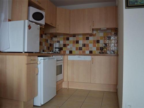 une cuisine avec des armoires en bois et un réfrigérateur blanc dans l'établissement Appartement confortable, 1 chambre, parking privé - FR-1-593-32, aux Angles