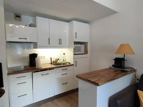 une cuisine avec des placards blancs et une table avec une lampe dans l'établissement Appartement T2 bis, 4-6 pers, centre ville, parking privatif, Cauterets - FR-1-234-263, à Cauterets