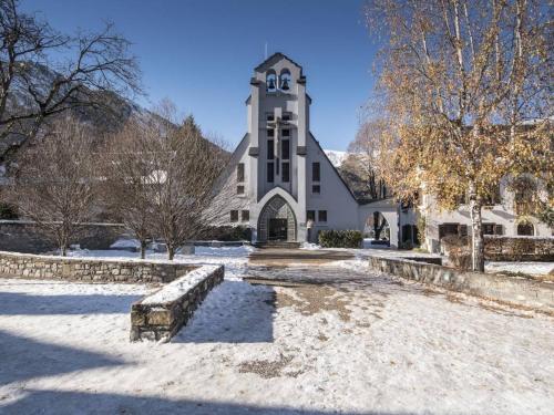 un grand bâtiment blanc avec une tour d'horloge dans la neige dans l'établissement Appartement 6 personnes, 2 chambres, proche pistes ski, Pla d'Adet - FR-1-296-360, à Saint-Lary-Soulan