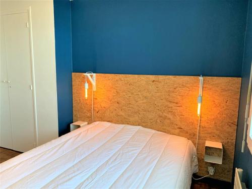 une chambre avec un grand lit avec un mur bleu dans l'établissement Quiberon - T2 50m² face mer, parking, animaux admis - FR-1-478-197, à Quiberon