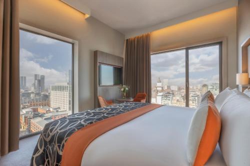 una camera d'albergo con un grande letto e ampie finestre di Clayton Hotel Manchester City Centre a Manchester