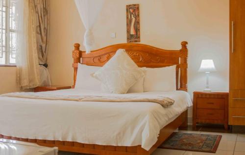 a bedroom with a large bed with a wooden headboard at Avon Garden Lodge in Salima