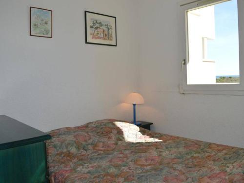 une chambre avec un lit avec une lampe et une fenêtre dans l'établissement Appart. en Bord de Mer avec Piscine, Parking et Animaux Acceptés - FR-1-225D-128, à Saint-Cyprien