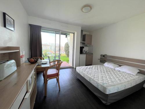 a bedroom with a bed and a table and a kitchen at Studio "Anémone" à Cambo, 2 pers., WIFI, animaux perm., parking - FR-1-495-100 in Cambo-les-Bains