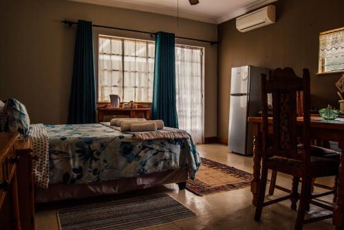 1 dormitorio con cama, escritorio y nevera en Farm stay at Fennel Cottage on Haldon Estate en Bloemfontein