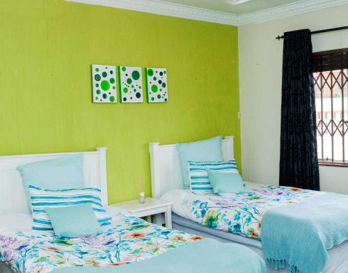 two beds in a room with green walls at KINGFISHER PLACE in Lenasia