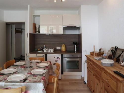 une cuisine avec une table avec des assiettes dessus dans l'établissement Appartement rénové 6 pers, balcon et animaux admis - FR-1-322-442, aux Orres