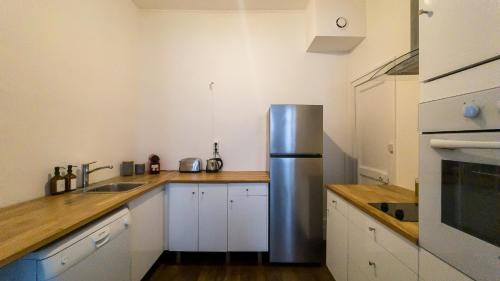 une cuisine avec un réfrigérateur en acier inoxydable et des armoires blanches dans l'établissement NOCNOC - Le Rayonnant, à Lyon