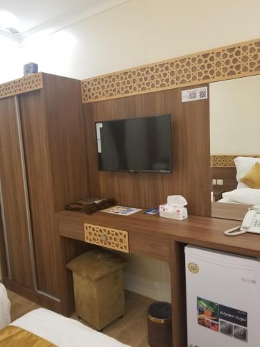 a room with a desk with a tv on it at Makkah Jewel Hotel in Makkah