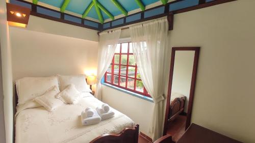 a bedroom with a bed and a window and a mirror at Casona 1865 in Ráquira