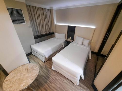 een hotelkamer met 2 bedden en een tafel bij Flat confortável ao lado da Paulista in Sao Paulo