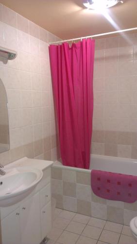 a bathroom with a pink shower curtain and a sink at Apartman 4 you Wellness in Budapest