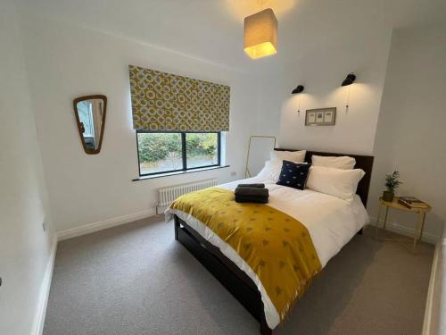 a bedroom with a large bed with a yellow blanket at Cheerful 2 bed house on Causeway Coastal Route with parking in Whiteabbey
