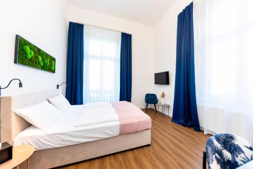 a bedroom with a large bed and blue curtains at Adagio Downtown Rooms in Budapest