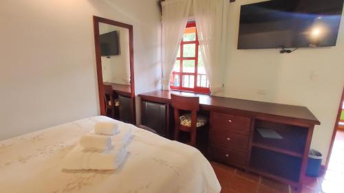 a bedroom with a bed and a dresser and a television at Casona 1865 in Ráquira