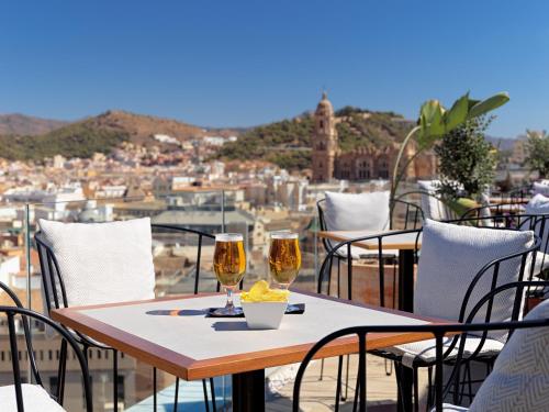 a table with two glasses of wine on a balcony at H10 Croma Málaga in Málaga