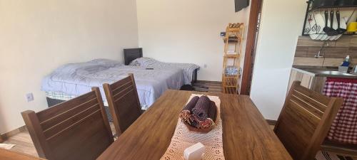 a dining room with a table and a bed at Pousada Colina das Maritacas in São Thomé das Letras