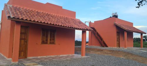 an orange house with a red roof at Pousada Colina das Maritacas in São Thomé das Letras