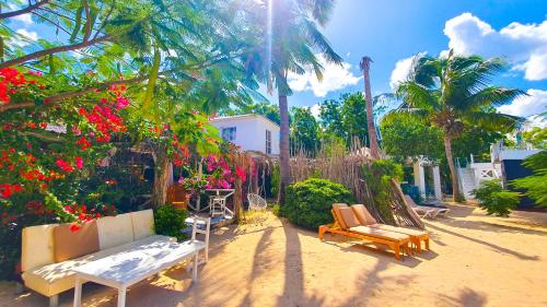 a patio with two couches and palm trees and flowers at Bluemare EcoHotel Frente a la playa Ensendada in Punta Rucia